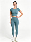 Premium Teal Short Sleeve Crop Top High‑waist Yoga Leggings Set, Female Model One‑Hand‑On‑Hip Standing Pose, Solid Color Stretchy Active‑wear Custom Outfit From Haideyu Apparel OEM ODM Service